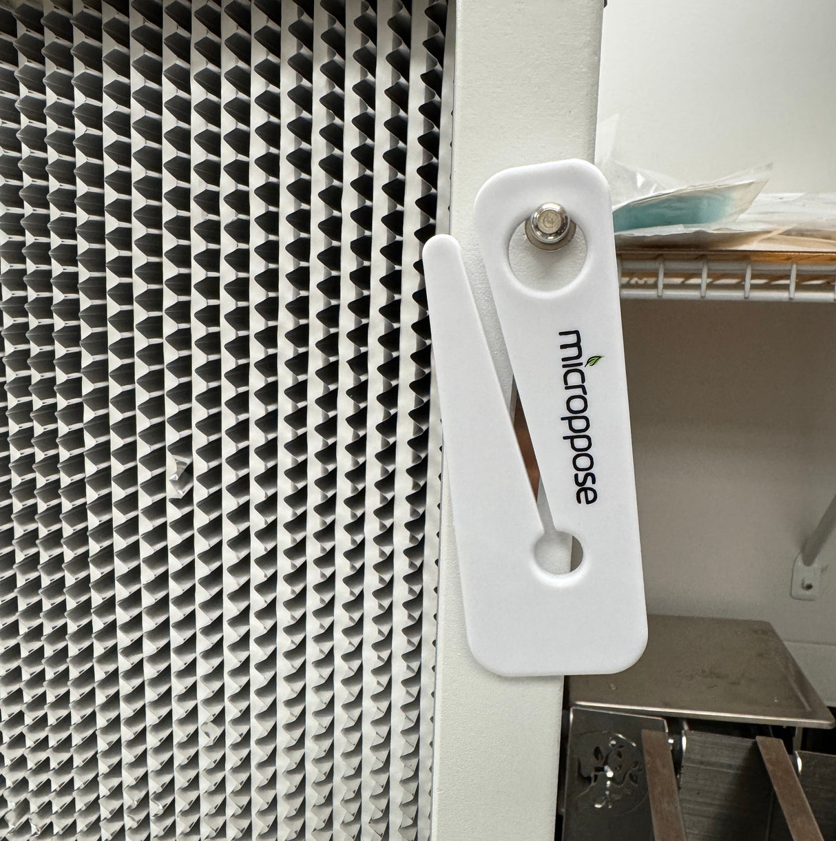 Microppose bag opener hanging by its hole on a laminar flow hood frame next to the HEPA filter