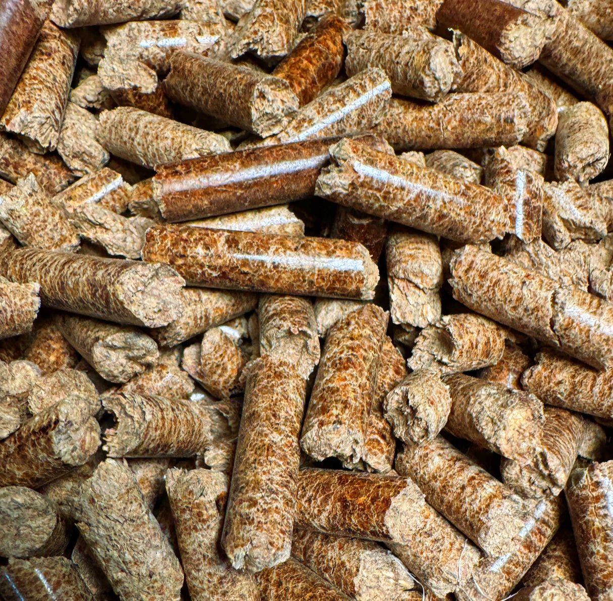 A close-up pile of cylindrical bamboo pellets in natural tan and brown tones, filling the entire frame.