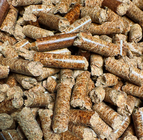 A close-up pile of cylindrical bamboo pellets in natural tan and brown tones, filling the entire frame.