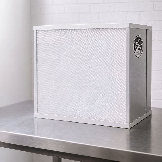 A white and silver Bonsai FFU Flow hood on a stainless steel work surface against a white brick wall background.