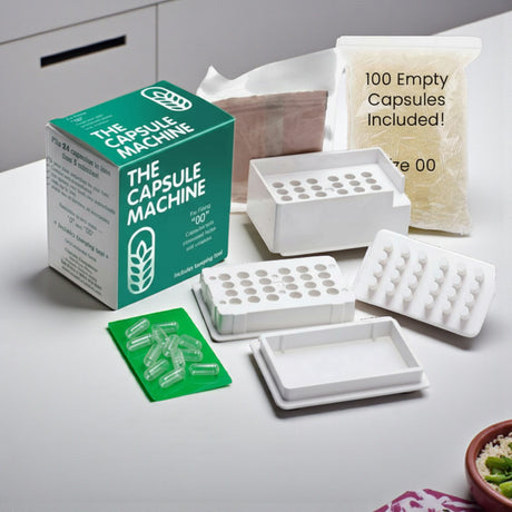 The Capsule Machine packaging with empty capsules and tools on a white surface