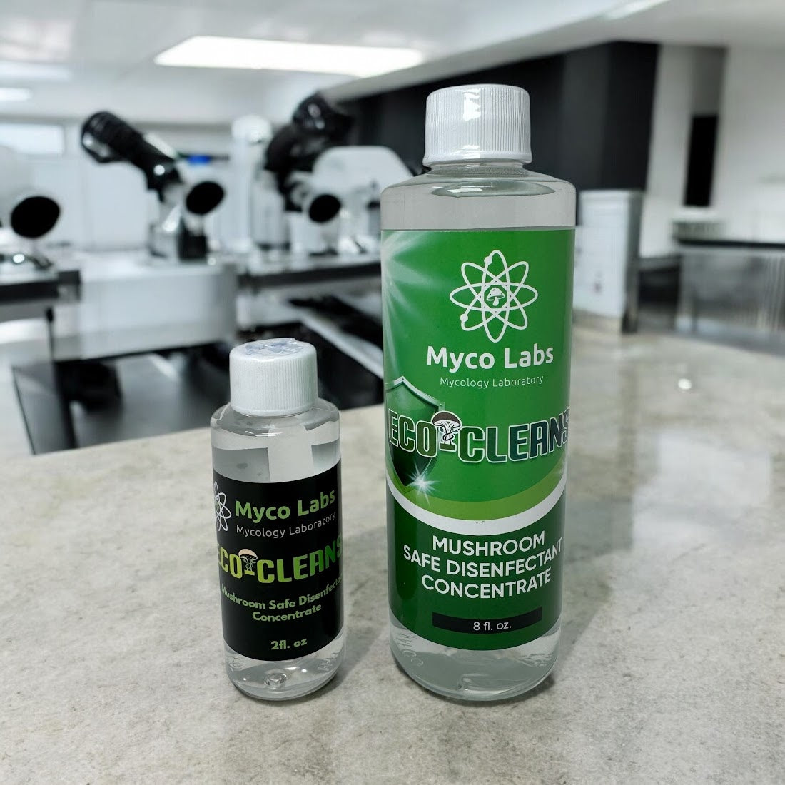 Two bottles of Myco Labs Eco-Clean on a countertop with laboratory equipment in the background.