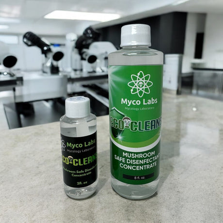 Two bottles of Myco Labs Eco-Clean on a countertop with laboratory equipment in the background.