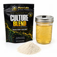 Myco Labs Culture Blend liquid culture premix shown with its black resealable pouch, a clear Ball wide-mouth jar filled with golden liquid, and a small pile of white powder on a white background.